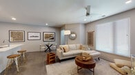 This single-floor unit is thoughtfully designed with a contemporary aesthetic that balances clean lines and warm, organic accents throughout. The open-concept layout connects the kitchen and living areas seamlessly, creating a cohesive and functional flow.

The kitchen features striking matte black cabinetry extending to the ceiling, black appliances, a white subway tile backsplash, and a white quartz peninsula with an undermount sink — offering both style and practicality. Recessed lighting and polished concrete floors reinforce the modern industrial character of the space.

The living area is bright and inviting, with large windows fitted with blinds allowing ample natural light. A ceiling fan, recessed lighting, neutral warm-toned walls, and concrete flooring continue throughout. A dedicated dining nook adds versatility to the space.

The bedroom is carpeted for comfort and includes a ceiling fan, a large window, and a wall-mounted electric fireplace with a floating media console — adding a refined, cozy focal point to the room.

The bathroom is finished with wood-look tile flooring, a sleek white vanity with a large mirror, sunburst decorative accents, and a spacious frameless sliding glass walk-in shower, completing the unit's polished, modern design.