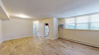Located at 28 Koster Blvd in Edison, NJ, this 2-bedroom, 1-bathroom residence offers a practical and well-organized single-floor layout. Light wood-look tile flooring runs throughout the living areas and bedrooms, creating a clean, cohesive aesthetic. The combined living and dining room provides an open, versatile space filled with natural light, anchored by a wall-mounted air conditioning unit and baseboard heating. A structural beam detail adds a subtle architectural element to the shared living space.

The kitchen features warm-toned wood cabinetry in an L-shaped configuration, light countertops, a stainless steel sink, and a gas range. A window above the sink brings in natural light and ventilation, while tile flooring and baseboard heating complete the space.

Both bedrooms are comfortably sized, with the primary bedroom offering generous proportions. Each room features the same light wood-look flooring, neutral walls, baseboard heating, and ample closet storage — three closets are distributed throughout the unit. The bathroom includes a full tub-shower combo with white tile surround, chrome fixtures, and a window for natural light. The overall ambiance is clean, bright, and move-in ready.