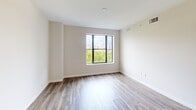 Located in the heart of Fort Lauderdale, this well-designed one-bedroom, one-bathroom residence offers a clean, modern aesthetic throughout. The open-concept kitchen and living area serves as the centerpiece of the unit, featuring sleek flat-front white cabinetry, a marble-style tile backsplash, stainless steel appliances including a French door refrigerator, electric range, and built-in microwave, and a large central island with pendant lighting — ideal for both cooking and casual dining. Wood-look flooring runs seamlessly throughout, adding warmth to the contemporary design. The spacious primary bedroom is flooded with natural light through large windows and a sliding glass door that opens onto a private balcony, offering open views of the surrounding Fort Lauderdale cityscape and lush tree canopy. The bathroom is elegantly appointed with marble-look tile flooring, a backlit vanity mirror, a quartz countertop with an undermount sink, and a glass-enclosed shower. A dedicated walk-in closet adjoins the bathroom, providing generous storage. The hallway connects all rooms efficiently, with additional closet space visible near the entryway. Track and pendant lighting throughout enhance the unit's bright, contemporary feel.