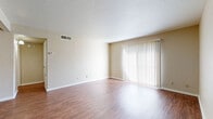 This single-floor unit offers a practical and well-organized layout with a clean, neutral aesthetic throughout. The living area is spacious and bright, featuring wood-look flooring that extends through the main living spaces. A large sliding glass door fitted with vertical blinds allows generous natural light to fill the room, creating an open and airy atmosphere. A textured ceiling and wall-mounted thermostat are functional details present in this area.

The kitchen is efficiently designed with warm-toned wood cabinetry lining both sides, providing ample upper and lower storage. White countertops, a stainless steel sink, and a full suite of stainless steel appliances—including a range, refrigerator, and dishwasher—are included. Recessed lighting illuminates the workspace effectively.

An adjoining dining or secondary living area connects to the kitchen and features a ceiling fan with a light fixture, continuing the wood-look flooring.

The bedrooms are carpeted and finished in soft neutral tones, each equipped with a ceiling fan and natural light from windows. The bathrooms are well-appointed, featuring granite-style countertops, warm wood vanity cabinetry, undermount sinks, brushed nickel fixtures, and a tiled tub-shower combination. A textured ceiling and multi-bulb vanity lighting complete each bathroom's functional design.