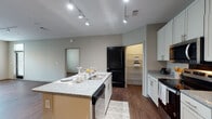 This single-story, 2-bedroom, 2-bathroom residence in Memphis, Tennessee offers a well-designed layout with modern finishes throughout. The open-concept kitchen serves as a central hub, featuring white shaker cabinetry, granite countertops, a large center island with a built-in sink and dishwasher, and stainless steel appliances including an electric range, microwave, and refrigerator. Track lighting illuminates the space, and a walk-in pantry with shelving provides ample storage. The kitchen flows naturally into the living area, which benefits from natural light through multiple windows and continues the rich hardwood-style flooring found throughout the unit.

Both bedrooms are well-proportioned, each with ceiling fans, large windows offering outdoor views, and the same hardwood-style flooring. The two bathrooms differ in configuration: one includes a tub-shower combination with white subway tile and a dark-cabineted vanity with granite countertops, while the second features a glass-enclosed walk-in shower, also finished in white subway tile, paired with a matching dark vanity and granite top. A walk-in closet with wire shelving is accessible from one of the bathrooms. The overall aesthetic is clean and contemporary, with neutral tones, consistent finishes, and an in-unit washer and dryer area visible from the kitchen.