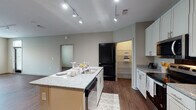 This single-story, 2-bedroom, 2-bathroom residence in Memphis, Tennessee offers a well-designed layout with modern finishes throughout. The open-concept kitchen serves as a central hub, featuring white shaker cabinetry, granite countertops, a large center island with a built-in sink and dishwasher, and stainless steel appliances including an electric range, microwave, and refrigerator. Track lighting illuminates the space, and a walk-in pantry with shelving provides ample storage. The kitchen flows naturally into the living area, which benefits from natural light through multiple windows and continues the rich hardwood-style flooring found throughout the unit.

Both bedrooms are well-proportioned, each with ceiling fans, large windows offering outdoor views, and the same hardwood-style flooring. The two bathrooms differ in configuration: one includes a tub-shower combination with white subway tile and a dark-cabineted vanity with granite countertops, while the second features a glass-enclosed walk-in shower, also finished in white subway tile, paired with a matching dark vanity and granite top. A walk-in closet with wire shelving is accessible from one of the bathrooms. The overall aesthetic is clean and contemporary, with neutral tones, consistent finishes, and an in-unit washer and dryer area visible from the kitchen.