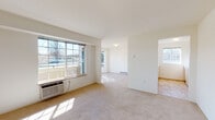 Located at 15408 E Fourth Ave in Spokane Valley, WA, this single-floor unit offers a clean, functional layout designed for comfortable everyday living. The open-concept living and dining areas are finished with plush wall-to-wall carpeting and neutral tones, creating a bright and airy atmosphere. Large windows allow abundant natural light to fill the space, with views of the surrounding neighborhood. Baseboard heating is present throughout, ensuring efficient climate control year-round, complemented by a wall-mounted AC unit in the living area.

The kitchen features warm wood-toned cabinetry, white appliances including a refrigerator, electric range, and microwave, and is open to the living area via a convenient breakfast bar with ample counter space. A dedicated in-unit laundry closet houses a full-size washer and dryer, adding practical convenience.

The bedroom is generously sized with carpet flooring, a large window, and baseboard heating. The bathroom includes a wide vanity with dual mirrors, light wood cabinetry, tile flooring, and an adjacent built-in shelving closet offering excellent storage. Additional rooms provide flexible use as a second bedroom or office. The overall design is straightforward, clean, and move-in ready.