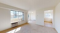 Located at 15408 E Fourth Ave in Spokane Valley, WA, this single-floor unit offers a clean, functional layout designed for comfortable everyday living. The open-concept living and dining areas are finished with plush wall-to-wall carpeting and neutral tones, creating a bright and airy atmosphere. Large windows allow abundant natural light to fill the space, with views of the surrounding neighborhood. Baseboard heating is present throughout, ensuring efficient climate control year-round, complemented by a wall-mounted AC unit in the living area.

The kitchen features warm wood-toned cabinetry, white appliances including a refrigerator, electric range, and microwave, and is open to the living area via a convenient breakfast bar with ample counter space. A dedicated in-unit laundry closet houses a full-size washer and dryer, adding practical convenience.

The bedroom is generously sized with carpet flooring, a large window, and baseboard heating. The bathroom includes a wide vanity with dual mirrors, light wood cabinetry, tile flooring, and an adjacent built-in shelving closet offering excellent storage. Additional rooms provide flexible use as a second bedroom or office. The overall design is straightforward, clean, and move-in ready.