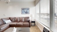 This well-appointed two-story residence in Columbus, Ohio offers three bedrooms and three bathrooms across a thoughtfully designed layout. The main floor is anchored by an open-concept living, dining, and kitchen area bathed in natural light. The kitchen is a standout feature, boasting dark espresso cabinetry, stainless steel appliances, a subway tile backsplash, and a central granite island with bar seating beneath sleek pendant lighting. A skylight overhead adds to the bright, airy atmosphere. The living area offers large windows with views of the Columbus skyline and surrounding neighborhood, complemented by warm wood-style flooring. The upper level hosts a bedroom with carpeted floors, a dedicated workspace, and an open-railed staircase that lends an airy, loft-like feel. The bedrooms are generously proportioned, each with plush carpeting and ample closet space. The bathrooms are clean and modern, featuring granite vanities, dark wood cabinetry, and tiled tub-shower combinations. Additional conveniences include a dedicated laundry room, a hallway connecting the private quarters, a balcony, and a patio — ideal for outdoor enjoyment. The overall ambiance is contemporary and functional, making this a comfortable and well-rounded urban residence.