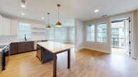 Located at 200 Henry Hill St in Cary, NC, this well-appointed single-floor residence offers a thoughtfully designed layout with modern finishes throughout. The open-concept kitchen serves as the heart of the home, showcasing two-tone cabinetry with white upper cabinets and slate-gray lower cabinets, sleek quartz countertops, a white subway tile backsplash, and stainless steel appliances. A central island with a light countertop and dark base is illuminated by warm gold pendant lights, while light hardwood flooring extends seamlessly into the adjacent dining area, which is brightened by multiple windows with white blinds. The spacious bedrooms feature plush carpeting, ceiling fans with integrated lighting, and windows that allow for ample natural light. The primary bathroom is generously sized with an extended double-vanity, quartz countertops, gold hardware accents, a glass-enclosed shower with tile surround, and direct access to a walk-in closet. A secondary bathroom offers a clean, functional design with a single vanity and a tub-shower combination. A dedicated laundry closet houses a stacked washer and dryer unit. Neutral tones, clean lines, and consistent modern hardware choices give this home a cohesive, contemporary aesthetic throughout.