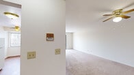 This single-floor space is designed with a straightforward, functional layout that maximizes usability across its rooms. The living area is finished with light neutral-toned carpet and crisp white walls, creating a clean and open atmosphere. A ceiling fan is overhead, and a wall-mounted intercom panel adds a practical detail near the entryway. Natural light enters through a window fitted with vertical blinds, contributing to a bright and airy feel.

The kitchen features warm-toned wood cabinetry both above and below the countertops, offering ample storage. A gas range, dishwasher, and stainless steel sink are integrated into the layout, and the space is finished with hardwood-style flooring that contrasts pleasantly with the white countertops. A doorway from the kitchen connects conveniently to the rest of the unit.

The bedrooms are carpeted and well-proportioned, with white walls and dark-stained wood closet doors that provide built-in storage with hanging rods. The bathroom includes a wood-base vanity topped with a white countertop and single basin sink, a large mirror, and a Hollywood-style light bar above.

Overall, the space maintains a clean, neutral aesthetic throughout.