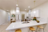 Located at 805 Roosevelt in Boise, Idaho, this thoughtfully designed two-story home offers 2 bedrooms and 2 bathrooms across two well-appointed floors. Light hardwood flooring and a neutral color palette of soft whites and warm wood tones create a cohesive, contemporary aesthetic throughout.

The main floor centers around a bright, open-concept living, dining, and kitchen area. The kitchen is a standout, featuring quartz countertops with marble-like veining, a large island with bar seating for three, two-tone cabinetry pairing white uppers with warm wood lowers, a premium range with a sleek hood, and glass pendant lights with brass accents. A well-organized walk-in pantry sits conveniently adjacent. Recessed lighting, a welcoming entrance hallway, and access to a private patio complete the ground level.

Upstairs, two bedrooms provide comfortable retreats, including a primary bedroom with direct outdoor access, multiple windows with natural light, and generous closet space. A dedicated laundry room with side-by-side washer and dryer adds everyday convenience. The two bathrooms are finished with quality fixtures — one featuring a tiled tub-shower combination with glass enclosure, the other a warm wood vanity with a dark countertop. A staircase connects both floors in a clean, modern style.