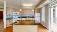 Located at 5101 Gateway St SE in Prior Lake, MN, this single-floor unit offers a well-designed layout with a range of functional features throughout. The kitchen serves as a central highlight, showcasing dark granite countertops that contrast attractively with light maple cabinetry. Pendant lighting hangs above a peninsula-style island, while white appliances, a tiled backsplash, and hardwood flooring complete the space. A tall, narrow window and a door leading to an outdoor area bring in natural light and provide convenient exterior access.

The living area is generously proportioned, featuring neutral carpet, large windows with vertical blinds, and an open connection to the kitchen that supports an airy, connected feel. Bedrooms are carpeted and bright, with windows overlooking the surrounding area. One bedroom includes access to a spacious walk-in closet equipped with multiple wire shelving units and hanging rods for ample storage.

Two full bathrooms are finished with tile flooring, wood-toned vanities with white countertops, and tub-shower combinations. The overall aesthetic throughout is clean and neutral, with a practical, well-organized layout suited for comfortable everyday living.