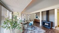 This two-story, 2-bedroom, 3-bathroom home delivers a functional and stylish layout across two well-proportioned floors. The main level opens into a welcoming living room featuring wood-look flooring, a textured ceiling with an eye-catching cove detail, and large sliding glass doors that flood the space with natural light and offer views of the surrounding greenery. A fireplace with built-in shelving anchors one end of the room, adding warmth and character. The kitchen is equipped with white shaker cabinetry, granite-style countertops, stainless steel appliances, and a breakfast bar — combining practicality with clean, modern aesthetics. Three full bathrooms throughout the home feature granite vanities, white cabinetry, and wood-look flooring. The spacious primary bedroom upstairs offers generous square footage, plush carpet, and a large window framing lush outdoor views. The second bedroom is equally well-sized, with wide windows, carpet flooring, and ample room for multiple uses. A dedicated laundry room with side-by-side washer and dryer adds everyday convenience. With two closets, four hallways, and a connecting staircase, the layout maximizes storage and flow throughout the home.