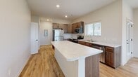 Located at 1220 West Highland Boulevard in Lincoln, Nebraska, this single-story, 3-bedroom, 2-bathroom home offers a clean, modern design with thoughtful finishes throughout. Light wood-look luxury vinyl plank flooring flows through the main living areas, complemented by neutral wall tones that create a bright and welcoming atmosphere. The living room features recessed lighting and multiple windows fitted with horizontal blinds, filling the space with abundant natural light and outdoor views. A glass exterior door provides additional access and further enhances the connection to the outdoors. The kitchen is well-equipped with warm wood cabinetry, stainless steel appliances including a refrigerator, range, and over-the-range microwave, and light stone countertops, including a generous island or peninsula. The bedrooms are carpeted and include ceiling fans, windows with outdoor views, and ample closet space across three dedicated closets. The bathrooms feature the same wood-look flooring as the main areas. An attached garage with a concrete floor and automatic door opener provides convenient, direct interior access. This home combines practical functionality with contemporary styling throughout.