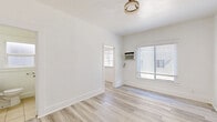 Located at 457 S Witmer St, Unit 206 in Los Angeles, CA, this one-bedroom, one-bathroom unit offers a efficiently designed layout across a single floor. The interior is finished with light-toned wood-style flooring throughout, complemented by crisp white walls that create a bright, clean aesthetic.

The bedroom is the largest room in the unit, featuring a large window with horizontal blinds that allows ample natural light to fill the space. A wall-mounted air conditioning unit provides individual climate control, and a flush-mount ceiling light fixture with a gold-toned finish adds a subtle decorative touch. A dedicated closet with a paneled white door provides organized storage.

The kitchen is well-appointed with white shaker-style cabinetry extending to the upper and lower walls, gray countertops, and a stainless steel sink. A striking marble-look tile backsplash adds visual interest, while stainless steel appliances — including a refrigerator and range — complete the functional cooking space. A window above the counter brings in additional natural light.

The bathroom features clean white tile walls and a tub/shower combination, finished with a brushed nickel door handle for a modern touch. The overall design of the unit is cohesive and contemporary, making efficient use of every square foot in this centrally located Los Angeles residence.