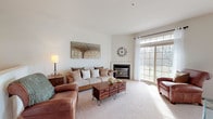 This three-story home is thoughtfully designed across multiple levels, offering a versatile layout suited for a variety of lifestyles. The main level features hardwood flooring throughout key areas, including the kitchen and a powder room. The kitchen is equipped with warm-toned wood cabinetry, granite countertops, stainless steel appliances including a gas range, built-in microwave, and dishwasher, all complemented by a deep sink and ample storage. A half bath on this level includes a classic pedestal sink and hardwood floors. The living room is a welcoming, carpet-floored space anchored by a gas fireplace and framed by large windows that invite natural light and outdoor views. An open staircase with wood railing connects the floors. Upstairs, carpeted bedrooms offer comfortable retreats, including one with a ceiling fan and natural light. A full bathroom features a soaking tub and shower combo. A dedicated laundry area with side-by-side washer and dryer adds everyday convenience. The finished lower level provides a spacious rec room with recessed lighting and carpet, alongside a quiet home office with built-in desk space and shelving—ideal for remote work or study.