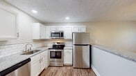 This well-appointed one-bedroom, one-bathroom unit in Lexington, Kentucky offers a thoughtfully designed single-floor layout with modern finishes throughout. The kitchen is a standout feature, boasting crisp white shaker-style cabinetry, granite countertops, a classic subway tile backsplash, and a full suite of stainless steel appliances including a range, over-the-range microwave, and refrigerator. Recessed lighting and a peninsula with additional granite countertop seating make the kitchen both functional and stylish, while an adjacent window fills the area with natural light and views of the surrounding greenery. Wood-look luxury vinyl flooring flows consistently throughout the entire unit, lending warmth and cohesion to each space. The open layout connects the kitchen seamlessly to the living area, creating a comfortable and versatile living environment. The bedroom is a well-proportioned, light-filled room featuring a ceiling fan, a window with outdoor views, and a closet. The full bathroom includes a tub/shower combination, a vanity with white cabinetry, and matching wood-look flooring. Neutral wall tones and clean white trim throughout contribute to a bright, move-in-ready atmosphere.