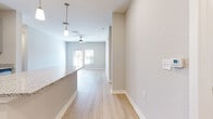 Located at 1000 Avida Village Circle in Orlando, Florida, this single-story, 3-bedroom, 2-bathroom home offers a clean, modern design with a bright and cohesive aesthetic throughout. The open living area features light wood-style flooring, a ceiling fan, and a glass door that invites natural light and outdoor views, creating an airy, welcoming atmosphere.

The kitchen is a standout feature, showcasing granite countertops, two-toned cabinetry, a subway tile backsplash, stainless steel appliances including a refrigerator with ice maker, range, microwave, and dishwasher, and pendant lighting above a generous island with additional storage beneath.

The three bedrooms are finished with plush carpet and offer ample closet space, including double-door closets in select rooms. The primary bedroom is spaciously sized with room for a full furniture arrangement. Both bathrooms mirror the home's modern finishes, featuring granite-topped white vanities, large mirrors, and light wood-style flooring. A dedicated in-unit laundry room accommodates a full-size washer and dryer with wire shelving above.

The hallway connects the living spaces efficiently, and the home's neutral color palette throughout creates a calm, move-in-ready environment.