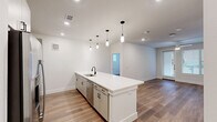 Located at 1735 N Greenville Ave in Richardson, TX, this well-appointed 2-bedroom, 2-bathroom unit offers a thoughtfully designed single-floor layout that maximizes functionality and comfort. The open-concept living and kitchen area serves as the heart of the home, anchored by a large central island with a crisp white quartz countertop, an undermount sink, and eye-catching pendant lighting. The kitchen is equipped with stainless steel appliances — including a French door refrigerator, electric range, and built-in microwave — complemented by grey shaker-style cabinetry and a classic subway tile backsplash. Warm wood-look flooring flows seamlessly throughout the entire unit, adding cohesion and a contemporary feel. Both bedrooms are bright and airy, featuring ceiling fans, generous natural light from multiple windows with blinds, and direct outdoor access in the primary bedroom. Each bedroom is paired with its own closet, offering ample storage. The two bathrooms are clean and modern, one featuring a tiled soaking tub-shower combination and quartz vanity surfaces. Two dedicated closets provide additional organization. The unit's neutral color palette and recessed lighting create a bright, welcoming ambiance throughout.