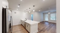 Located at 1735 N Greenville Ave in Richardson, TX, this well-appointed 2-bedroom, 2-bathroom unit offers a thoughtfully designed single-floor layout that maximizes functionality and comfort. The open-concept living and kitchen area serves as the heart of the home, anchored by a large central island with a crisp white quartz countertop, an undermount sink, and eye-catching pendant lighting. The kitchen is equipped with stainless steel appliances — including a French door refrigerator, electric range, and built-in microwave — complemented by grey shaker-style cabinetry and a classic subway tile backsplash. Warm wood-look flooring flows seamlessly throughout the entire unit, adding cohesion and a contemporary feel. Both bedrooms are bright and airy, featuring ceiling fans, generous natural light from multiple windows with blinds, and direct outdoor access in the primary bedroom. Each bedroom is paired with its own closet, offering ample storage. The two bathrooms are clean and modern, one featuring a tiled soaking tub-shower combination and quartz vanity surfaces. Two dedicated closets provide additional organization. The unit's neutral color palette and recessed lighting create a bright, welcoming ambiance throughout.