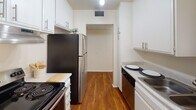 Located at 400 N Chapel Ave in Alhambra, California, this single-floor residence offers a practical and comfortable layout designed for everyday living. The kitchen is a standout feature, configured as a galley-style space with white cabinetry, brushed nickel hardware, light granite-style countertops, and warm hardwood flooring. Stainless steel appliances — including a refrigerator, electric range, and dishwasher — provide a modern, cohesive look. Track lighting and a ceiling fan add both function and style to the adjoining dining or living area. The living area is generously sized, bathed in natural light streaming through vertical blinds on a sliding glass door, and finished with plush carpet that transitions seamlessly to the hardwood in the kitchen. The bedroom features the same soft carpeting underfoot, a ceiling fan with light fixture, a mirrored sliding-door closet, and a window that fills the room with natural light. The bathroom is clean and well-appointed, featuring a full tub-shower combination with brushed nickel fixtures and a classic white surround. Throughout the space, textured ceilings and neutral tones create a bright, welcoming atmosphere.