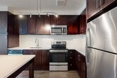 Located at 3445 Berkley St in Alexandria, VA, this well-designed 2-bedroom, 2-bathroom unit offers a thoughtfully laid-out single-floor plan with a generous amount of living space. The entrance opens into a bright, open-concept dining and living area, providing a versatile space for everyday living and entertaining. The modern kitchen is a standout feature, boasting white shaker-style cabinetry extending to the ceiling, gray quartz countertops, a white subway tile backsplash, and a full suite of stainless steel appliances including a refrigerator, dishwasher, and electric range. Rich wood-look flooring runs throughout the main living areas, adding warmth and continuity. Both bedrooms are carpeted and receive natural light through large windows with outdoor views of greenery. The primary bedroom offers a comfortable, well-proportioned retreat. The bathrooms feature light tile flooring, white vanities, and one is equipped with accessibility grab bars. A dedicated den provides flexible space for a home office or additional living area. Five closets throughout the unit ensure ample storage. In-unit laundry adds everyday convenience, completing this practical and modern residence.