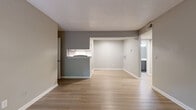 Located at 6619 Yateswood Dr in Charlotte, NC, this single-floor residence offers two bedrooms and two full bathrooms in a thoughtfully laid-out floor plan. The open living and dining area greets you upon entry, featuring light-toned hardwood-style flooring, neutral gray walls, and a sliding glass door that fills the space with natural light and provides views of the surrounding greenery. A pass-through window connects the living area to the galley-style kitchen, which is well-equipped with gray shaker cabinetry, white quartz countertops, a subway tile backsplash, stainless steel appliances including a refrigerator, electric range, and dishwasher, and a stainless undermount sink. Both bathrooms are finished with gray vanity cabinets, white countertops, large-format marble-look tile in the shower and tub surrounds, and wood-style flooring. The two bedrooms are carpeted for comfort, each featuring neutral gray walls and windows that overlook wooded outdoor scenery. The primary bedroom includes a walk-in closet. A connecting hallway ties the layout together efficiently, making for a clean and functional flow throughout the home.