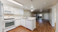 Located at 1530 W Avenue K-8h in Lancaster, CA, this single-floor residence offers 2 bedrooms and 3 bathrooms within a well-organized layout. The open-concept kitchen flows seamlessly into the combined dining and living area, creating a spacious, connected feel. The kitchen is outfitted with white cabinetry, light granite-style countertops, a full suite of white appliances including a gas range, built-in microwave, dishwasher, and refrigerator, plus a double sink. Warm hardwood-style flooring runs throughout the main living spaces, complemented by a ceiling fan overhead. A sliding glass door in the living room opens to a private balcony, allowing natural light to fill the area. Both bedrooms feature plush carpeting and windows that bring in additional daylight. The primary bedroom includes an en-suite bathroom with a granite-topped vanity and hardwood-style flooring. The bathrooms are finished with clean white fixtures and tub-shower combinations with grab bars. Additional conveniences include two closets, a dedicated laundry area, and a hallway connecting the main rooms. The neutral color palette throughout provides a calm, versatile backdrop.
