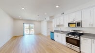 This single-floor unit offers a clean, contemporary design highlighted by light hardwood flooring that runs seamlessly throughout every room, creating a bright and cohesive aesthetic. The open-concept layout connects the kitchen directly to the living area, maximizing the sense of space and encouraging a natural flow between the two zones. A sliding glass door in the living area opens to an outdoor balcony, inviting natural light deep into the interior.

The kitchen is well-appointed with crisp white shaker-style cabinetry extending to the ceiling for generous storage, complemented by gray stone countertops and a full suite of stainless steel appliances, including a gas range, over-the-range microwave, and dishwasher. Additional counter space and cabinetry extend into an adjacent nook, offering further utility near the entry door.

The bedrooms are spacious and bright, each featuring built-in closets with shelving and hanging rails for organized storage. Recessed lighting throughout the unit maintains a clean ceiling profile while ensuring consistent illumination.

The bathrooms mirror the home's modern palette, featuring white vanity cabinetry with gray countertops, large mirrors, and light hardwood-style flooring. One bathroom includes a tub and shower combination with sliding glass doors, while the other offers a streamlined vanity and toilet layout.