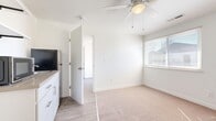 This efficiently designed single-story unit offers a well-organized layout across one bedroom, one bathroom, a kitchen, and a dedicated laundry area. The interior maintains a consistent, clean aesthetic with bright white walls and neutral tones throughout.

The kitchen features white shaker-style cabinetry, a stainless steel refrigerator, a gas range with an overhead exhaust hood, and light wood-look vinyl flooring. A corridor view from the kitchen reveals direct access to the stacked washer and dryer unit, which is tucked neatly into its own enclosed laundry space—a notably practical inclusion.

The bedroom is a comfortable size, finished with soft carpet, a ceiling fan with a light fixture, a window with blinds that allows natural light, and a sliding-door closet offering built-in shelving and hanging space.

The bathroom is clean and functional, featuring a full tub-shower combination with white subway tile surround, brushed nickel fixtures, and wood-look vinyl flooring that coordinates with the rest of the unit.

The main living area also features a ceiling fan, a window with natural light, and a transition between carpet and vinyl flooring. The overall ambiance is bright, tidy, and move-in ready.