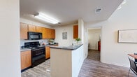 This two-story residence offers a well-organized layout across two nearly equal floors, providing ample space for comfortable living. The main floor features an open-concept kitchen equipped with warm honey-toned cabinetry, dark granite-style countertops, black appliances including a range and dishwasher, and a peninsula that doubles as a breakfast bar. Wood-look flooring flows throughout the main living areas, connecting the kitchen to a combined dining and living space. The living room stands out with impressively tall ceilings that enhance the sense of openness, complemented by natural light from a window with blinds. The adjacent dining area provides a defined space for meals without sacrificing the open feel of the floor plan.

Each of the four bedrooms features its own dedicated closet outfitted with wire shelving systems for organized storage, and carpeted walk-in closets are present in select rooms. The primary bedroom includes a ceiling fan and natural light from a window. The four bathrooms are consistently finished with wood-toned vanity cabinetry, granite-style countertops, and tub-shower combinations. A hallway and staircase connect the two floors, creating a functional and cohesive flow throughout the home.