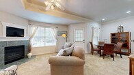 Located at 2600 W 6th St in Lawrence, Kansas, this single-floor, 2-bedroom, 2-bathroom home offers a thoughtfully designed layout that maximizes comfort and functionality. The living room serves as the heart of the home, featuring a tiled fireplace surround, plush carpeting, a tray ceiling with a ceiling fan, and multiple windows that fill the space with natural light. A dedicated dining area adjoins the living space, enhancing the open feel. The kitchen is equipped with white cabinetry accented with gold trim, dark countertops, glass-front upper cabinets, and a peninsula breakfast bar with seating — ideal for casual dining. A full suite of appliances including a refrigerator, range, microwave, and dishwasher complete the kitchen. The primary bedroom features a distinctive tray ceiling with crown molding, ceiling fan, and direct access to an en-suite bathroom with a vanity and tiled flooring. A second bedroom offers similar comfort with carpeted floors and ceiling fan lighting. Both bathrooms include tiled flooring, with the second bathroom featuring a shower-tub combination with glass sliding doors. A dedicated in-unit laundry area accommodates a full-size washer and dryer. Two closets provide ample storage throughout the home.