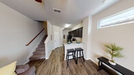 Located at 2131 Indian Creek Rd in Brownwood, Texas, this two-story residence offers a thoughtfully designed layout across two levels. The main floor showcases an open-concept living and kitchen area with durable wood-look plank flooring throughout. The kitchen is a standout feature, equipped with dark espresso cabinetry, granite-look countertops, and stainless steel appliances including a refrigerator, electric range, and microwave. A peninsula with bar seating provides a casual dining option, while a high transom window allows natural light to brighten the living space. A carpeted staircase with a wooden handrail connects the floors, and a convenient half bathroom is situated on the main level, complete with granite countertops. Upstairs, the bedrooms offer plush carpeting, ceiling fans, and windows that bring in natural light. The bedrooms feature neutral tones and closet access, creating comfortable and functional retreats. The overall aesthetic is clean and contemporary, with a neutral color palette, modern fixtures, and a cohesive design that flows naturally throughout both floors.