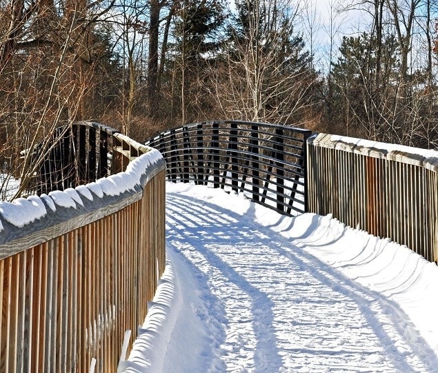 A pedestrian bridge leads over the Clinton River in River Woods Park
