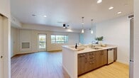 Located at 11490 Black Falcon Dr in Auburn, CA, this well-appointed 2-bedroom, 2-bathroom single-story home offers a thoughtfully designed open-concept layout. The combined living, dining, and kitchen area serves as the heart of the home, featuring light hardwood-style flooring, recessed lighting, and a ceiling fan. The modern kitchen is equipped with stainless steel appliances, dark wood cabinetry, a large center island with a quartz countertop, an undermount sink, and stylish pendant lighting. A door from the living area opens directly to a balcony, flooding the space with natural light and providing pleasant outdoor views. Both bedrooms are carpeted and include ceiling fans, with the primary bedroom featuring vaulted ceilings, walk-in closet access, and views of the surrounding landscape. The bathrooms are finished with light tile flooring, white cabinetry, stone-toned countertops, and clean, modern fixtures. A dedicated laundry room houses a full-size washer and dryer with overhead cabinetry for additional storage. With four closets throughout, ample storage is a consistent feature of this home. The overall ambiance is bright, clean, and contemporary, reflecting a move-in-ready residence designed for functional and comfortable living.