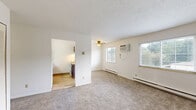 Located on Cleveland Avenue Northwest in Canton, Ohio, this single-floor, 2-bedroom, 1-bathroom home offers a straightforward and functional layout. The living room features wall-to-wall carpet, a textured ceiling, and a wide window fitted with horizontal blinds that allows natural light to fill the space. White wainscoting panels line the lower walls, adding a subtle decorative detail. A baseboard heating system runs along the exterior walls throughout the home. Both bedrooms are carpeted and include ceiling fans, windows with outdoor views of surrounding greenery, and louvered bi-fold closet doors providing ample storage. The primary bedroom is a comfortable size with a double-door closet, while the secondary bedroom mirrors the same clean, neutral aesthetic. The full bathroom features light wood-toned flooring, a dark wood vanity with a light countertop, and a full tub-and-shower combination with white tile surround. The kitchen, visible in the floor plan, is positioned adjacent to the main living areas and includes standard appliances. Throughout the home, neutral wall colors, consistent carpeting, and functional finishes create a clean, move-in ready environment well-suited for everyday living.