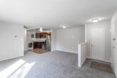 This single-floor unit offers a practical and well-organized layout spread across multiple rooms. The living area is generously sized, finished with neutral gray carpet, and features a sliding glass door that fills the space with natural light while providing access to an outdoor area. A second living or dining area connects directly to the kitchen, creating an open, functional flow between spaces.

The kitchen is well-appointed with rich dark cabinetry, granite-style countertops, and a full suite of stainless steel appliances, including a gas range with over-the-range microwave and a refrigerator. A stainless steel sink completes the workspace. Notably, in-unit laundry is accommodated within the kitchen area, offering added convenience.

The bedrooms are carpeted and bright, each featuring windows that bring in natural light and views of the surrounding landscape. Each bedroom includes a closet, with at least one featuring a walk-in style layout. The bathroom is clean and straightforward, with a tiled tub-shower combination, a dark-vanity with a white countertop, and wood-look flooring. The unit's neutral color palette and consistent finishes contribute to a cohesive, move-in-ready ambiance throughout.