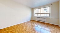 Located along Lake Shore Boulevard West in Toronto, this 2-bedroom, 1-bathroom unit offers a practical and well-organized single-floor layout. The living room is a standout space, featuring gleaming parquet wood flooring in a classic herringbone pattern and a large window that invites an abundance of natural light, with radiator heating situated beneath. The warm, neutral-toned walls create a bright and airy atmosphere throughout.

The primary bedroom is a generously sized room with light wood laminate flooring, a window providing natural light and views of the surrounding neighbourhood, and convenient access to a dedicated closet. The second bedroom mirrors a similar aesthetic, with its own parquet flooring, closet storage, and a welcoming, sunlit character.

The unit includes a total of three closets, offering practical storage solutions throughout. The bathroom features classic white tile walls, a full bathtub with shower, a pedestal sink, a mirrored medicine cabinet, and a charming black-and-white mosaic tile floor.

The entrance leads smoothly into the main living areas, and the kitchen completes the functional layout. Overall, the unit presents a clean, classic character with consistent flooring, neutral finishes, and a straightforward design well-suited for comfortable city living.