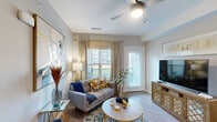 This single-floor unit offers a thoughtfully designed layout that maximizes its compact footprint. The open-concept living and kitchen area serves as the heart of the space, where hardwood-style flooring flows throughout. The kitchen is a functional standout, featuring rich dark-toned cabinetry, light granite countertops, a large central island with pendant lighting, stainless steel appliances including a refrigerator, range, and microwave, plus a textured tile backsplash that adds visual interest. The adjacent living room receives natural light through multiple windows with exterior views, and is equipped with a ceiling fan overhead and direct access to an exterior door.

The bedroom is generously sized, finished with plush carpet, a natural light window, decorative floating shelves, and a dedicated closet. Neutral gray wall tones throughout the unit create a calm, cohesive ambiance. The bathroom features dark wood cabinetry with a single vanity, a framed mirror, open shelving, and a glass-enclosed shower. Overall, the unit presents a modern, well-finished interior designed for comfortable single-occupant or couple living.