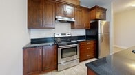 Located at 15 Bently Dr in Halifax, Nova Scotia, this well-appointed 3-bedroom, 1-bathroom unit offers a comfortable and functional single-floor layout. The open-concept living and kitchen area serves as the heart of the home, bathed in natural light from large windows that frame beautiful views of surrounding trees. The living room features warm hardwood-style flooring, a classic fireplace, and a sliding glass door that enhances the connection to the outdoors. A pendant-lit ceiling fixture adds a stylish focal point to the space.

The kitchen is thoughtfully designed with rich dark wood cabinetry, dark granite countertops, a breakfast bar, and a full suite of stainless steel appliances, including a range, refrigerator, and dishwasher. The tile flooring in the kitchen provides a clean contrast to the rest of the unit.

Three well-sized bedrooms offer hardwood-style floors and generous windows with peaceful, tree-lined views. The primary bedroom provides a notably spacious retreat. The full bathroom includes a soaking tub and shower combination with tile flooring and matching wood vanity cabinetry. A dedicated laundry room with side-by-side washer and dryer adds everyday convenience, while two closets provide ample storage throughout the unit.