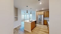 Located at 14000 Tapestry Dr in Orlando, FL, this single-floor residence offers three bedrooms, two bathrooms, and a thoughtfully designed layout. Light wood-style flooring runs through the main living areas, complemented by neutral tones that create a bright, cohesive atmosphere throughout.

The kitchen is a standout feature, outfitted with natural wood cabinetry, white subway tile backsplash, white quartz countertops, and a full suite of stainless steel appliances including a French door refrigerator, electric range, and built-in microwave. A kitchen island with a sink and pendant lighting adds both function and style, opening toward the living area for a seamless flow.

The primary bedroom is generously sized, featuring multiple windows that invite abundant natural light and an outdoor view, along with a ceiling fan. Additional bedrooms are carpeted and well-proportioned, each with closet access. The primary bathroom includes a walk-in shower with white subway tile surround, a wood-toned vanity, and white countertops. The second bathroom mirrors this aesthetic with a tub-shower combination and matching finishes.

A dedicated laundry room houses a full-size washer and dryer with overhead shelving. Three closets provide ample storage throughout the home.