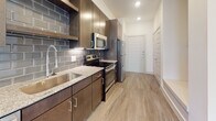 Located at 950 Town Lake Dr in College Station, TX, this single-floor unit offers a thoughtfully designed layout with contemporary finishes throughout. The open living area is bright and airy, featuring light hardwood-style flooring, recessed lighting, and a ceiling fan that enhances comfort and airflow. Large sliding glass doors lead to a private balcony, allowing abundant natural light to fill the space and providing a seamless connection to the outdoors.

The kitchen is well-appointed with rich dark cabinetry, granite countertops, a stainless steel undermount sink with a modern pull-down faucet, and a full suite of stainless steel appliances including a refrigerator, range, and over-the-range microwave. A striking subway tile backsplash adds a stylish, contemporary touch, complementing the overall design aesthetic.

The bedroom is generously sized, featuring the same hardwood-style flooring, a ceiling fan with a light fixture, and direct access to the bathroom. The bathroom is finished with a dark wood vanity, granite countertop, an undermount sink, a large mirror, and chrome hardware accents, creating a clean and polished look. The space as a whole maintains a neutral, modern palette that is both functional and visually cohesive.