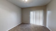 This single-story residence offers a practical and well-organized layout designed for comfortable everyday living. The living area is spacious and carpeted, featuring a textured ceiling, a ceiling light fixture, and a large sliding glass door fitted with vertical blinds that floods the space with natural light. This area flows openly toward the kitchen, which is separated by a partial wall and breakfast bar. The kitchen is equipped with white cabinetry, laminate countertops, a double-basin sink, a dishwasher, a refrigerator, a microwave, and wood-look flooring, providing a clean and functional cooking environment.

The bedrooms are carpeted and neutral in tone, each featuring ceiling fans with light fixtures and windows dressed with horizontal blinds. At least one bedroom includes access to a walk-in closet. The two full bathrooms each feature a tiled shower-tub combination, white vanity cabinetry, laminate countertops, a mirror, wall-mounted storage, and wood-look flooring. Textured ceilings are consistent throughout the unit. The overall color palette is neutral, creating a calm and move-in-ready atmosphere throughout.