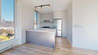 Located at 2125 Rue Ward in Montréal's Saint-Laurent borough, this well-designed 4-bedroom, 2-bathroom unit offers a bright, modern living experience across a single floor. Light hardwood flooring flows throughout, complementing the clean white walls and creating a cohesive, airy atmosphere.

The contemporary kitchen serves as a functional centerpiece, featuring a large island with an integrated sink and dishwasher, sleek grey cabinetry reaching to the ceiling, stainless steel appliances, and track lighting. Tall windows flood the kitchen with natural light and offer open views of the surrounding neighbourhood.

Each of the four bedrooms is well-proportioned, with large windows that bring in ample daylight. Several bedrooms showcase exposed concrete columns and ceilings, adding an industrial touch that contrasts nicely with the otherwise clean, minimalist aesthetic. The primary bedroom provides a comfortable and private retreat.

The two bathrooms are finished in a modern style with wood-look flooring, grey floating vanities, and mirrored medicine cabinets. One bathroom features a soaking tub with an overhead rain shower, while the second includes a glass-enclosed walk-in shower. Two hallways connect the layout efficiently, and a dedicated closet adds practical storage. The unit's design balances functionality with contemporary style throughout.