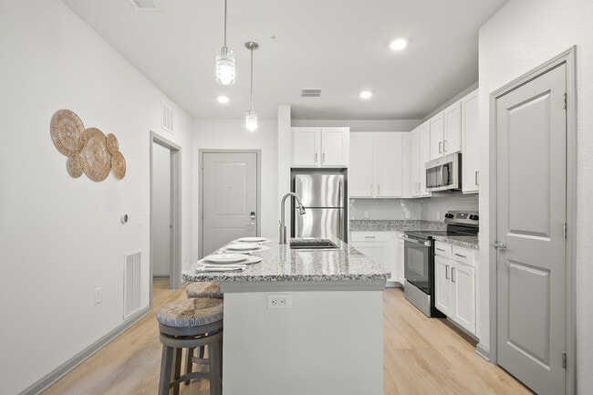 Modern kitchen interior with sleek granite countertops, stainless steel appliances, and stylish bar seating. Bright and inviting space perfect for culinary creativity. - Avana Parkway