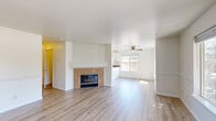 Located at 339 SE Reed Market Rd in Bend, Oregon, this 2-bedroom, 2-bathroom single-floor residence offers a practical and comfortable layout. The open living area is anchored by a tile-surround fireplace and features light-toned laminate flooring that extends throughout the common spaces, creating a bright and cohesive feel. A ceiling fan adds to the comfort of the living room, which receives natural light through a large window. The kitchen is well-appointed with white cabinetry, dark countertops, a peninsula, recessed lighting, and white appliances including a refrigerator, range, and dishwasher. Multiple windows frame views of the surrounding trees and neighborhood, filling the space with natural light. The primary bedroom offers carpeted flooring and a generous window overlooking mature trees. The second bedroom also features carpet and a dedicated closet with an in-unit stacked washer and dryer. Both bathrooms are finished with clean, functional fixtures, including a tub-shower combo with white tile surround and a vanity with mirror. A hallway connects the bedrooms and bathrooms, keeping the layout efficient. The overall ambiance is clean, neutral, and move-in ready.