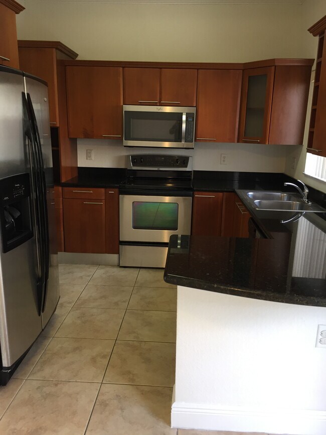 Cocina con electrodomésticos de acero inoxidable y granito negro. - 17802 NW 74th Ct