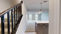 This two-story residence offers 1,030 square feet of well-organized living space across two floors of approximately 530 and 510 square feet respectively. The main level features a combined kitchen and living room area. The kitchen is outfitted with stainless steel appliances including a gas range, built-in microwave, refrigerator, and dishwasher, complemented by two-tone cabinetry with dark lower and white upper cabinets, light quartz countertops, a tile backsplash, and light ceramic tile flooring. A window above the sink provides natural light. The living room is a spacious, open area with warm neutral-toned carpet and two large windows offering views of lush outdoor greenery. The upper level hosts two carpeted bedrooms, each featuring ceiling fans and windows that allow natural light. The primary bedroom measures 180 square feet and includes louvered closet doors for storage. All three bathrooms are consistently finished with light beige ceramic tile flooring, dark wood vanities with white countertops, and full soaking tub/shower combinations surrounded by neutral square tile surround. A hallway and closet complete the layout, making this home a functional and cohesive living space.
