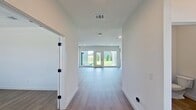 Located at 3505 Oxenfree Blvd in Rowlett, TX, this contemporary two-story home offers 3,410 square feet of well-designed living space across 7 bedrooms and 6 bathrooms. The first floor spans 1,850 square feet and features an open-concept kitchen and living room, a dedicated living room, and a welcoming entrance. The kitchen is appointed with two-tone cabinetry — light wood upper cabinets paired with dark lower cabinets — complemented by a tile backsplash, stainless steel appliances, and light wood-look flooring that flows throughout the main level. The living room opens directly to the outdoors through large glass doors, flooding the space with natural light and providing backyard access. The second floor covers 1,560 square feet and houses the majority of the bedrooms, including a primary suite of 220 square feet with a walk-in closet featuring built-in wire shelving. The primary bathroom includes a long dual-sink vanity with ample cabinetry, a framed mirror, and black hardware accents. Bedrooms feature plush carpet flooring, ceiling fans, and windows with outdoor views. A well-lit laundry room with washer and dryer hookups and large windows completes the upper level. The home's clean, neutral palette and modern finishes create a bright, cohesive ambiance throughout.