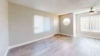 Located at 1455 E Date St in San Bernardino, CA, this single-floor, 2-bedroom, 2-bathroom home offers a clean and functional layout designed for comfortable everyday living. Light wood-style flooring runs throughout the unit, complementing the neutral gray and white color palette that gives the space a bright, modern feel. Textured ceilings add a classic touch present in every room.

The open-concept living, dining, and kitchen area forms the heart of the home. The kitchen features white cabinetry with ample upper and lower storage, light countertops, and a peninsula that opens to the living and dining space — ideal for casual meals and entertaining. The living area receives natural light through a large window fitted with vertical blinds, and a front entry door adds a welcoming focal point.

The primary bedroom is a standout, highlighted by a distinctive circular porthole-style accent window that adds architectural character, along with a standard window for additional natural light and a ceiling fan for year-round comfort. Both bedrooms include sliding-door closets and share the same warm, neutral flooring. Each of the two bathrooms is finished in crisp white with a tub/shower combination and brushed metal fixtures. A connecting hallway ties the layout together efficiently, making the most of the home's well-organized footprint.