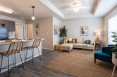 Located on Clovis Road in Lubbock, Texas, this single-floor residence offers a thoughtfully designed open-concept layout that seamlessly connects the main living areas. The living room is bright and welcoming, featuring wood-look flooring, a ceiling fan with integrated lighting, tray ceiling detailing, and large windows fitted with horizontal blinds that allow generous natural light to fill the space.

The kitchen is a functional centerpiece of the home, outfitted with dark wood cabinetry, light countertops, and a full suite of black appliances including a refrigerator, range, microwave, and dishwasher. A peninsula with pendant lighting and bar seating provides both additional prep space and a casual dining option that connects directly to the living area.

The bedrooms are comfortably sized, each featuring wood-look flooring, ceiling fans or ample lighting, and windows that bring in natural light. The rooms offer a calm, neutral palette well-suited for rest and relaxation.

The bathroom is clean and practical, featuring a tub-shower combination, wood-look flooring, and overhead cabinetry for additional storage.

Throughout the home, consistent wood-look flooring, neutral wall tones, and modern fixtures create a cohesive and contemporary aesthetic that is both functional and inviting.