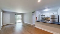 Located at 1410 East Butler Pike in Ambler, PA, this single-floor residence offers a practical and well-appointed layout across two bedrooms, two bathrooms, and a thoughtfully organized living space. Light-toned hardwood-style flooring runs throughout, lending a clean, cohesive look to the entire unit.

The open living area is bright and airy, with soft neutral walls and a sliding glass door that invites natural light and provides direct access to a private patio with views of surrounding greenery. The kitchen features a raised breakfast bar with a dark countertop, white cabinetry, recessed lighting, and a stainless steel range, flowing seamlessly into the living space.

The primary bedroom is generously sized, featuring a closet, a window with natural light, and easy access to the hallway. The second bedroom is well-proportioned with its own closet and a similarly neutral palette. Both bedrooms offer warm hardwood-style flooring and ample wall space.

The two bathrooms are finished in a clean, modern style with white vanities, mirrored medicine cabinets, black fixture accents, and tiled tub-shower combinations. Additional features include three closets for storage, a dedicated laundry area, and a hallway connecting the home's key spaces efficiently. The overall ambiance is clean, functional, and move-in ready.