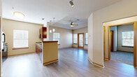 This single-floor residence offers a thoughtfully designed layout that balances open communal spaces with private retreats. The heart of the unit is an open-concept living and dining area, finished with wood-look plank flooring that extends throughout the main spaces. A tray ceiling with a ceiling fan adds architectural interest to the living room, which is bathed in natural light from multiple windows and a glass door that opens to an outdoor balcony.

The kitchen is well-appointed with rich, dark-stained cabinetry, granite countertops, a tile backsplash, and a full suite of black appliances including a refrigerator, range, microwave, and dishwasher. A breakfast bar peninsula connects the kitchen to the living area, enhancing the open flow. Light wood-look flooring ties the kitchen seamlessly into the main living space.

The bedrooms are carpeted for comfort, each featuring ceiling fans and ample natural light. One bedroom includes a spacious walk-in closet outfitted with wire shelving and hanging rods. Additional rooms offer hardwood-style flooring and generous closet storage. A hallway connects the private quarters, with a full bathroom featuring a tiled tub-shower combination and tile flooring completing the space.